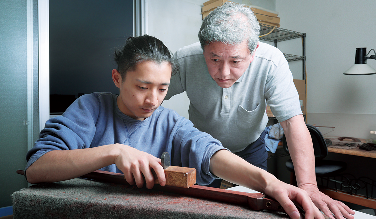 2人の弟子を指導しつつ、三絃司きくおかで三味線づくりを行う河野公昭氏(写真右)。「三味線は、皮の素材やなめし方、木材の質などで音が大きく変 わります。その点、私たちは海外企業から材料を直接輸入していますから、楽器に最適な素材を選べるのが強みなのです」(河野氏)