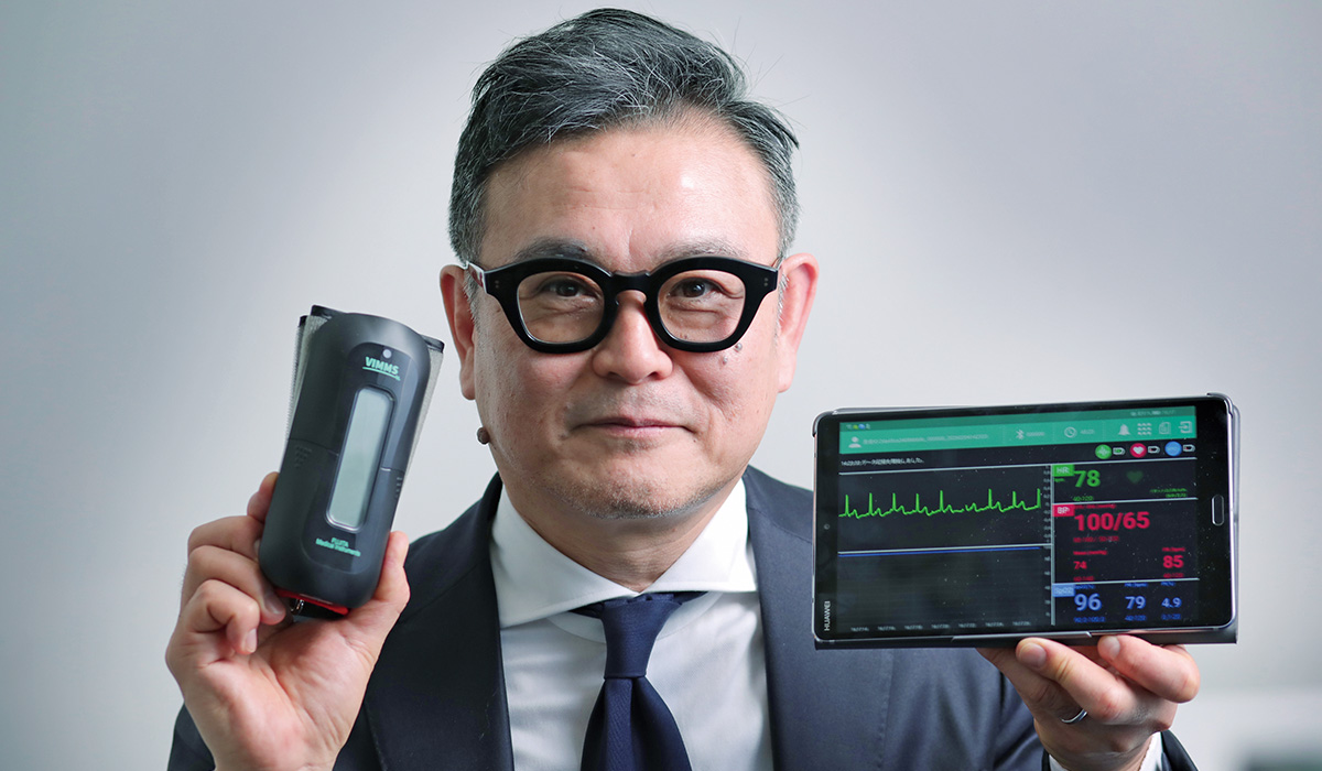 代表取締役の前多宏信氏が手にしているのは、リモート生体情報マルチモニター「VIMMS」。血液中の酸素飽和度や血圧、心拍データを1つの小型機器で計測し、安価なAndroid端末タブレットに送信できる点が高く評価され、在宅医療や救急医療の現場で広まっている